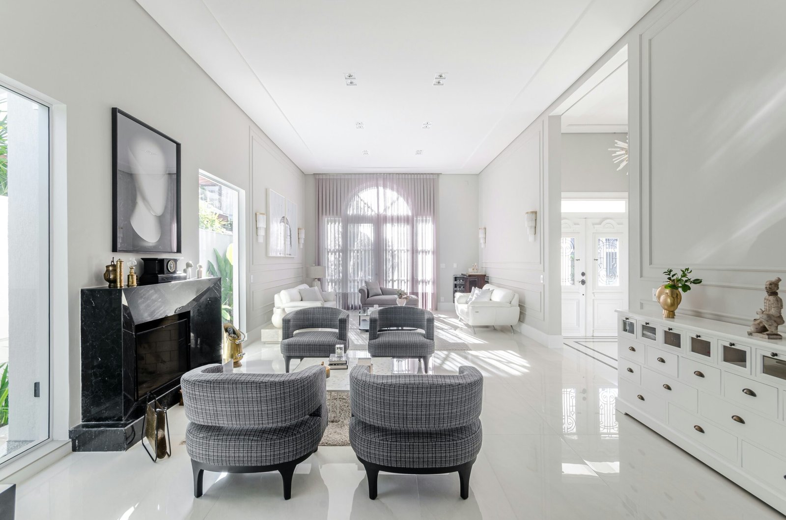 image of a beautiful bright clean living room with light gray walls, white shining tile floors, and dark gray furniture