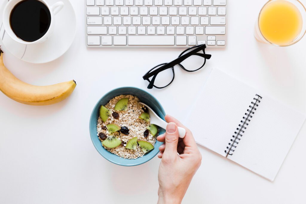 Calm morning scene with a laptop, coffee, orange juice, and muesli bowl on a white table — symbolizing peaceful, predictable mornings and easy routines.